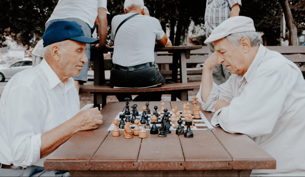 Una pareja de ancianos jugando al ajedrez en un parque al aire libre