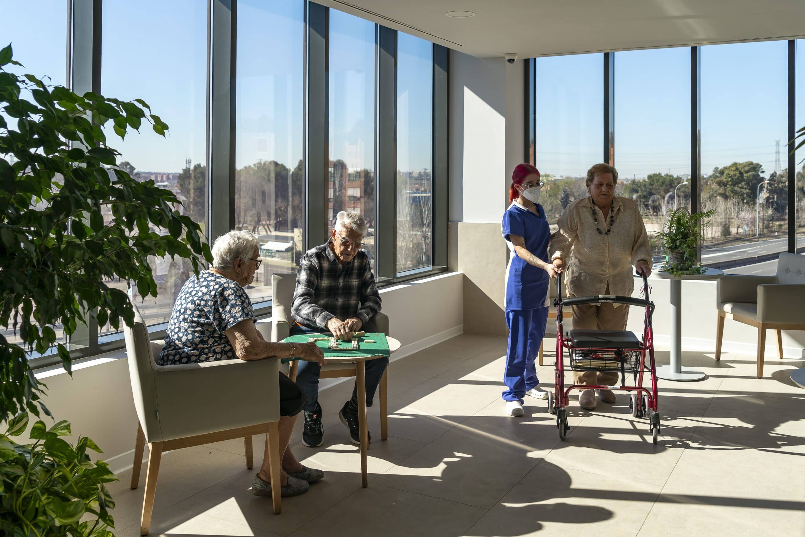 Mujer paseando y pareja jugando al parchís en una residencia de mayores